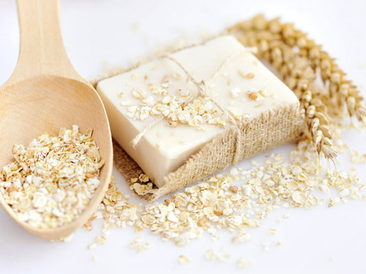 A bar of Oatmeal Soap next to a wooden spoon full of oats
