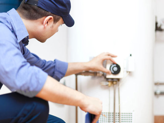 A plumber checking the hot water heater's temperature gauge