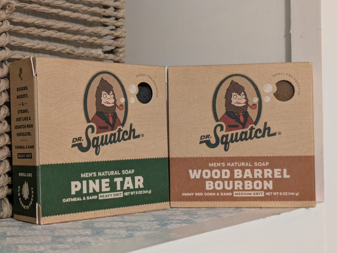 Two packaged bars of Dr. Squatch Men's Natural Bar Soaps. Pine Tar Scent on the left and Wood Barrel Bourbon on the right.