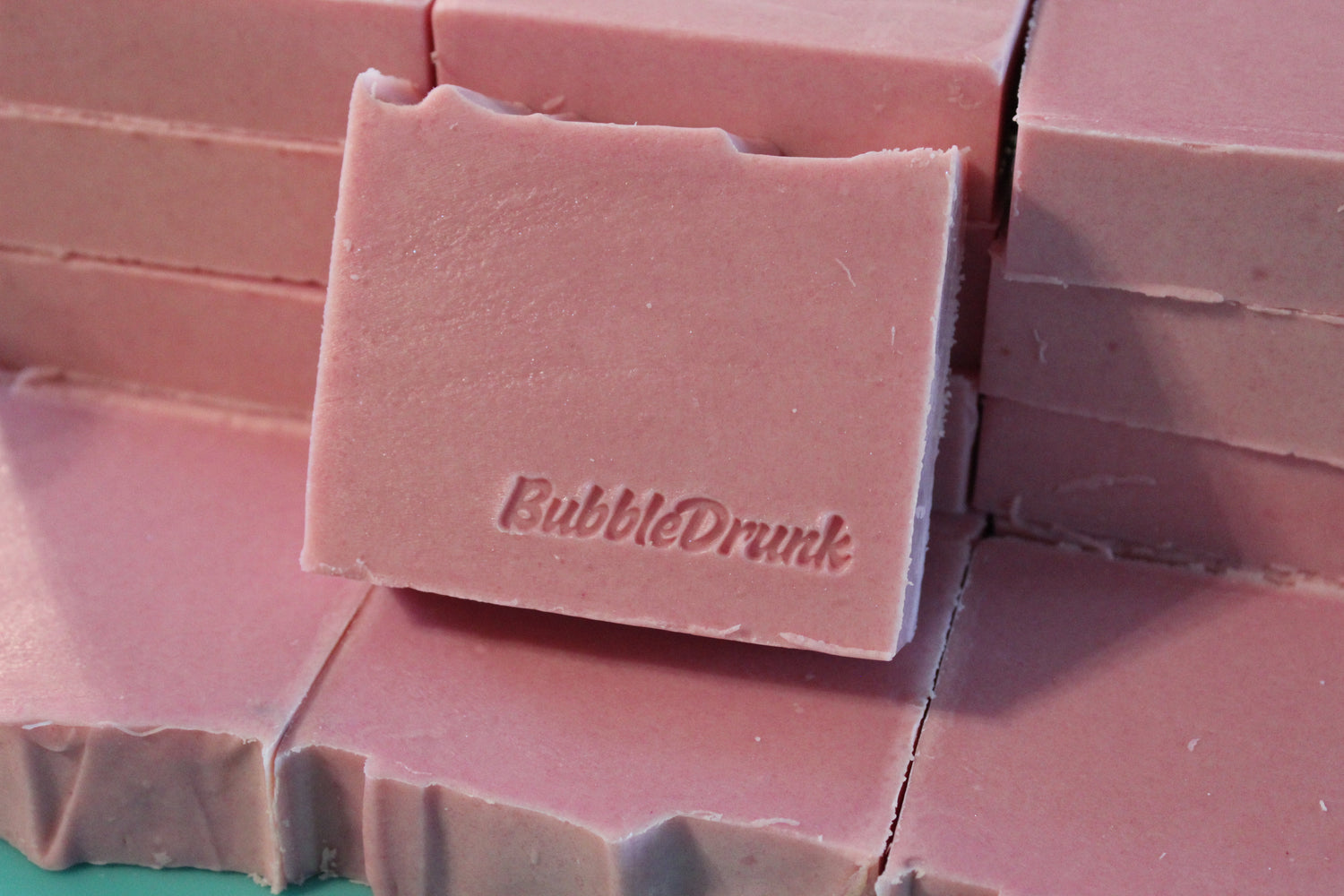 A stack of pink handmade bars of BubbleDrunk soap.