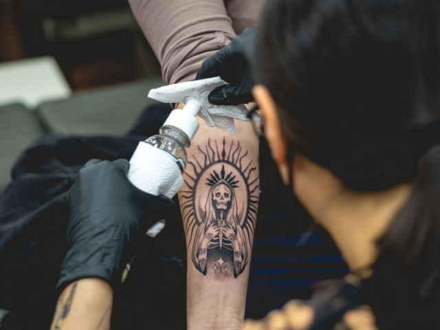 A tattoo artist cleaning a recently finished tattoo
